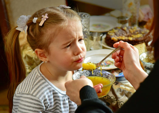 Little girl being feed a spoonful of soup