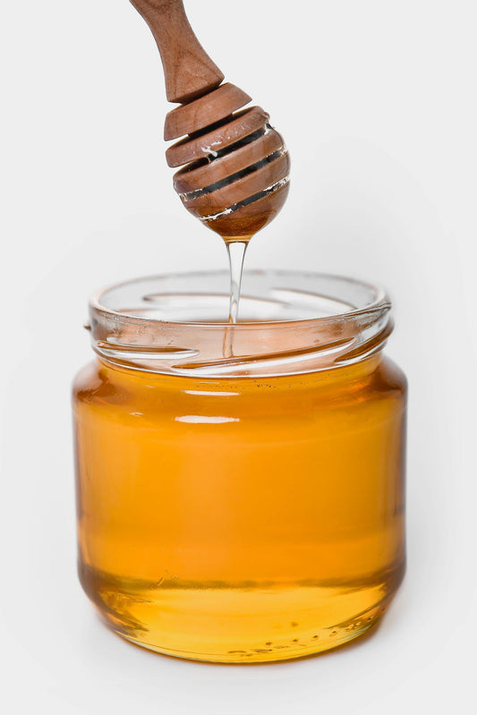 Honey dripping into a jar from a spoon showing honey thick consistency