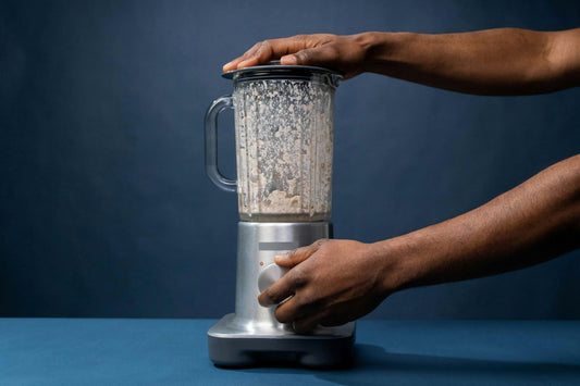 Two hands holding a blender, blending bread