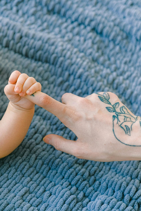 A baby's hand holding onto a mother's finger suggesting hopefulness