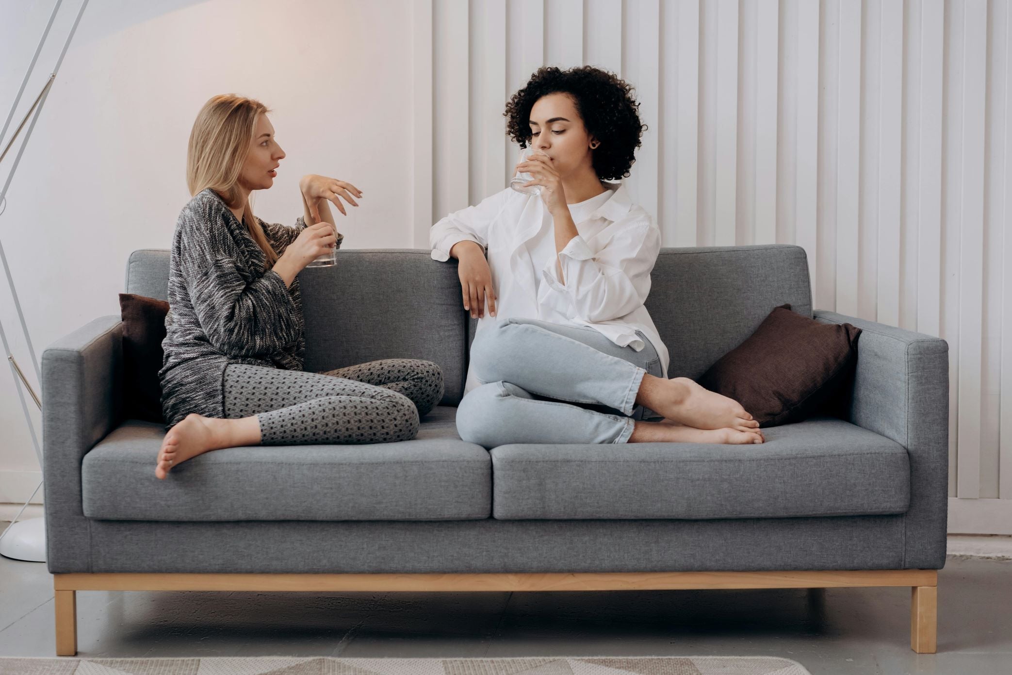 Two friends chatting on a couch drinking water