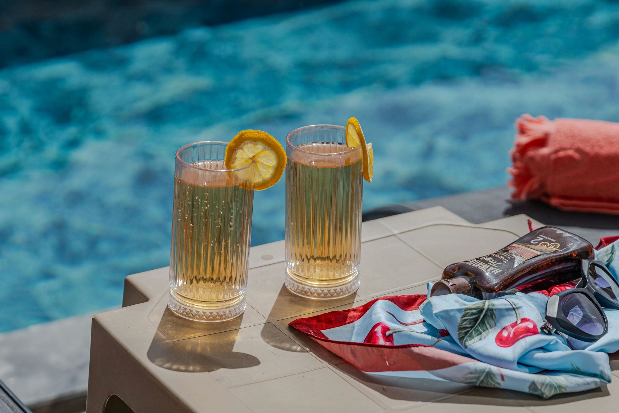 Two glasses of juice on the edge of a pool